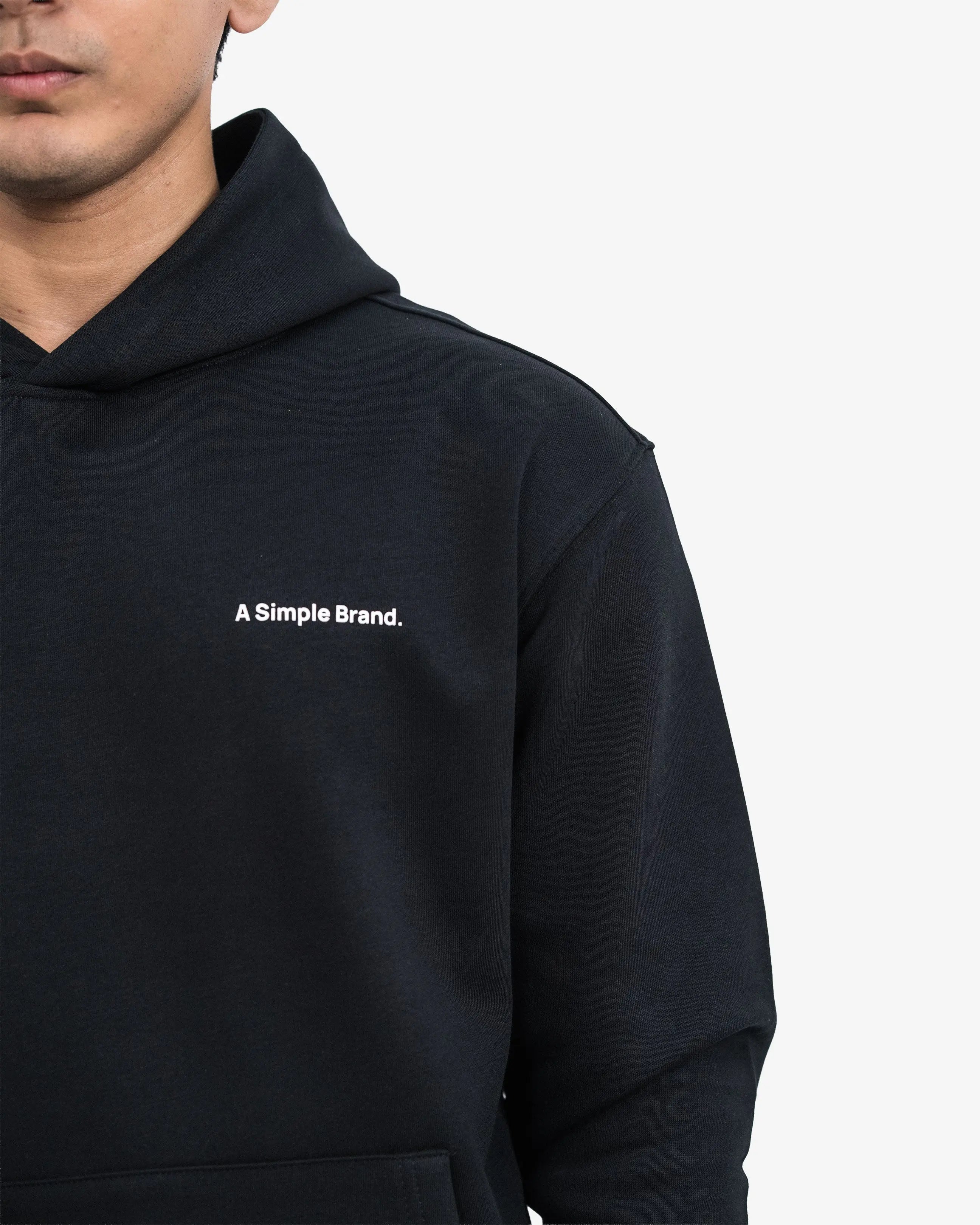 Person wearing a black hoodie with 'A Simple Brand' logo on a white background