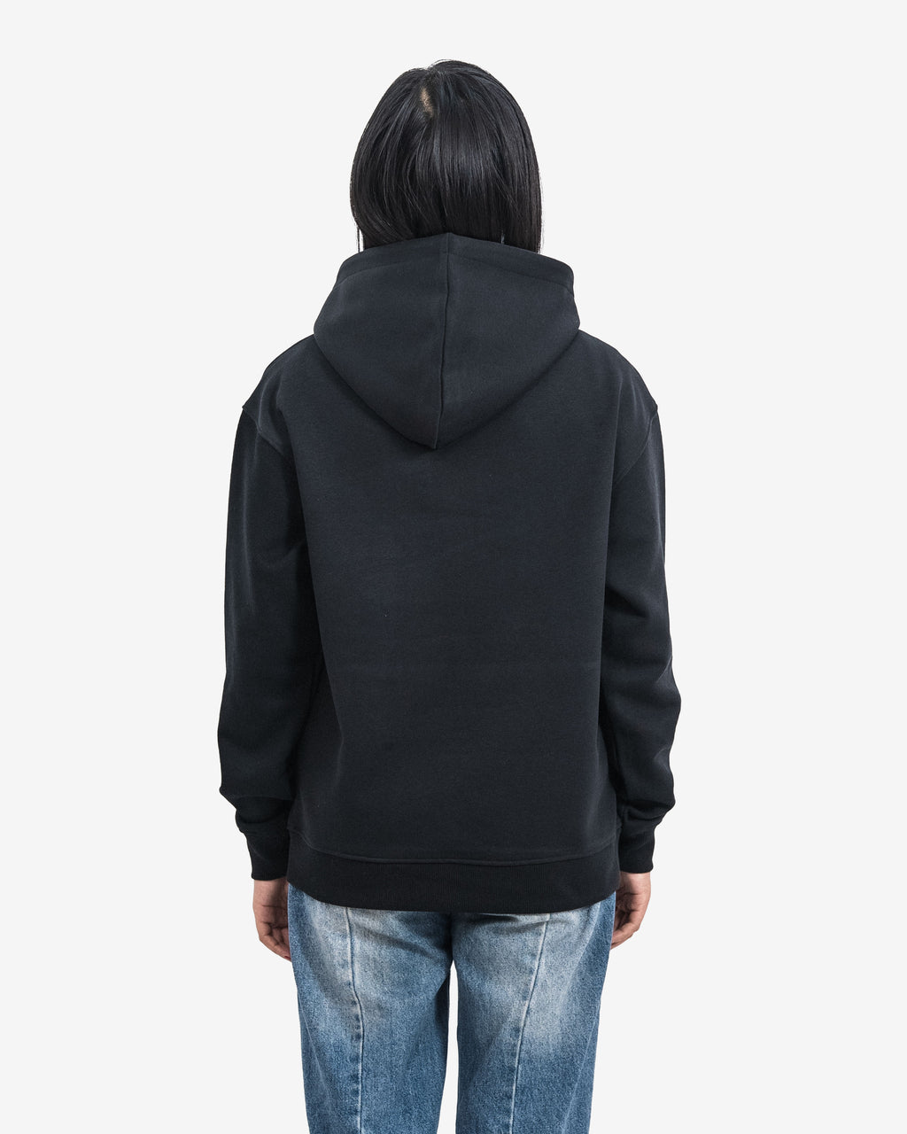 Person wearing a black hoodie and blue jeans on a white background