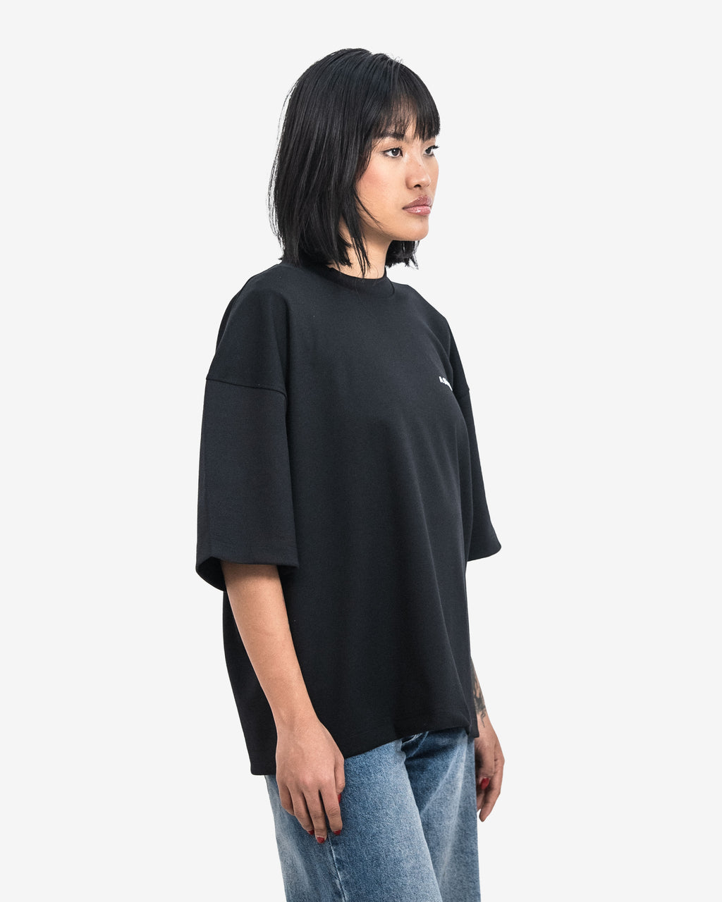 Person wearing a black oversized t-shirt and blue jeans on a white background
