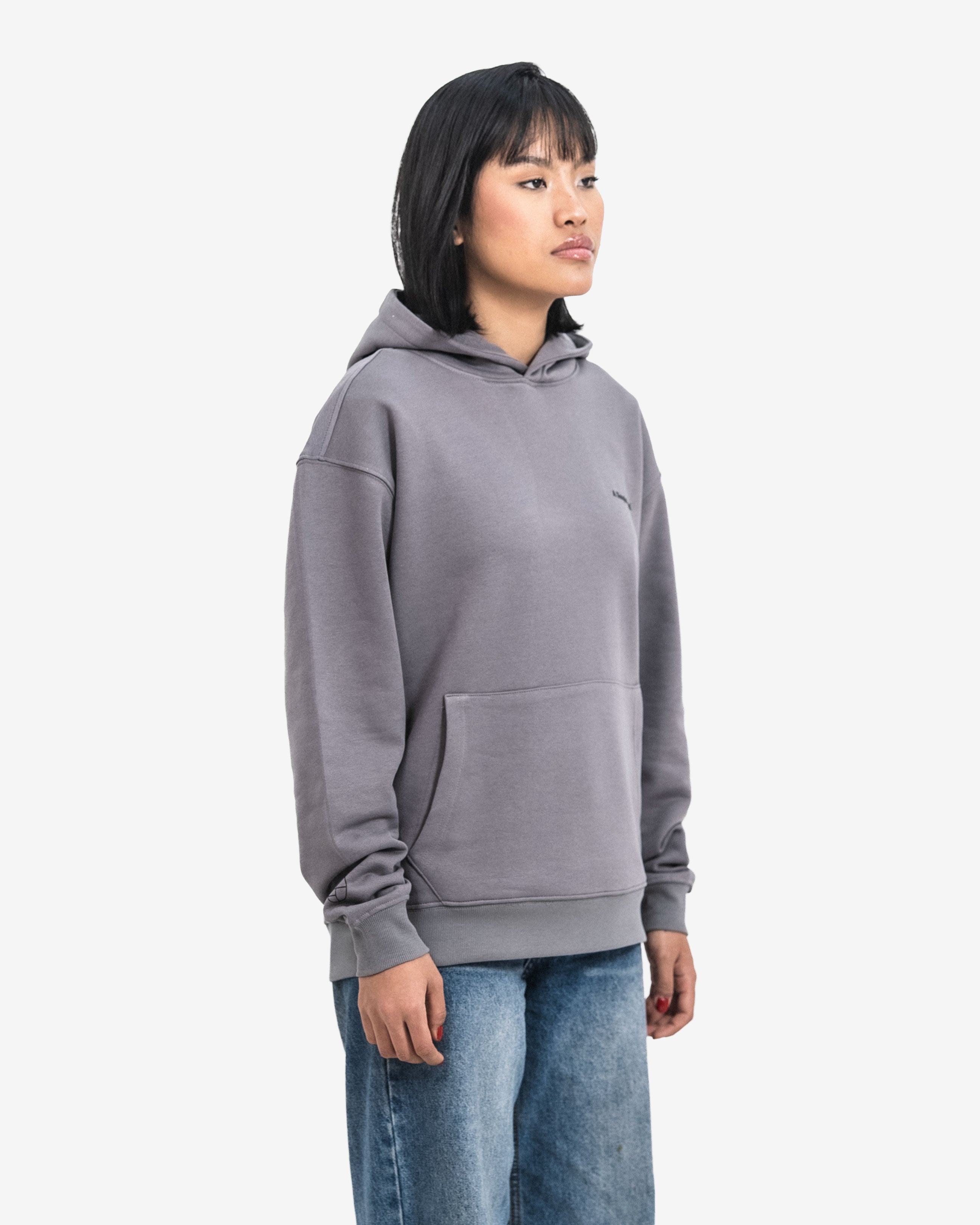 Person wearing a gray hoodie and blue jeans on a white background